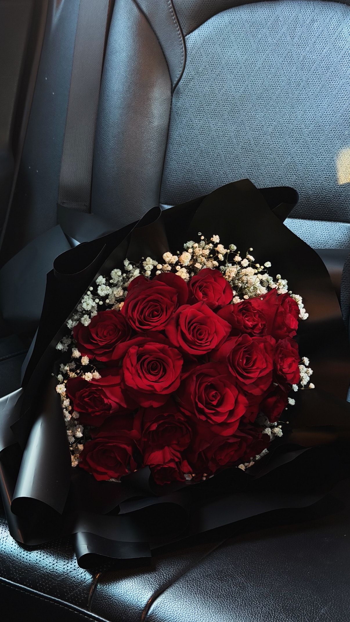 Bouquet of red roses in black wrapping paper with baby's breath