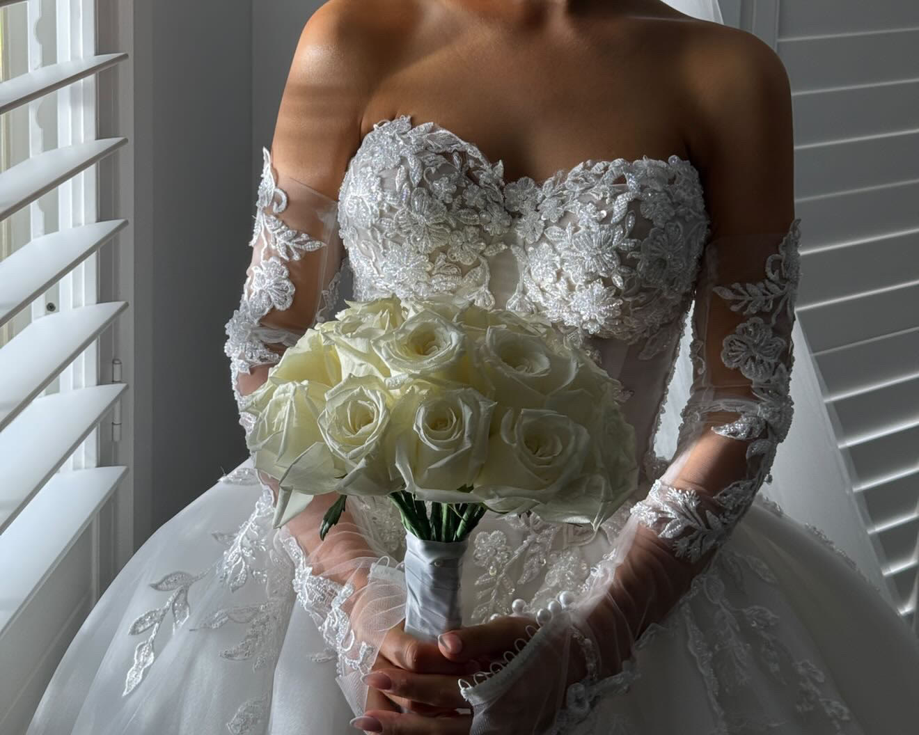 Bride in a lace gown holding a bouquet of white roses