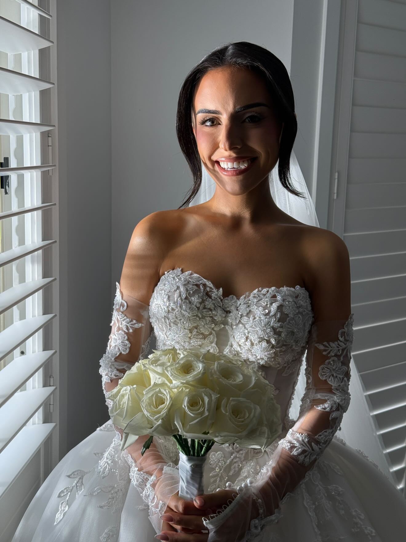 Bride smiling, holding a bouquet of white roses