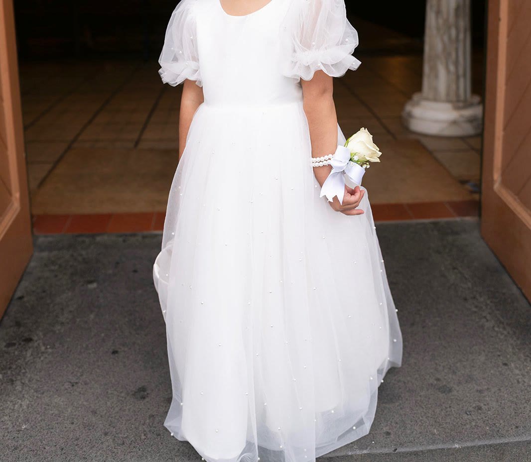 Flower girl in a white tulle dress with a rose wrist corsage